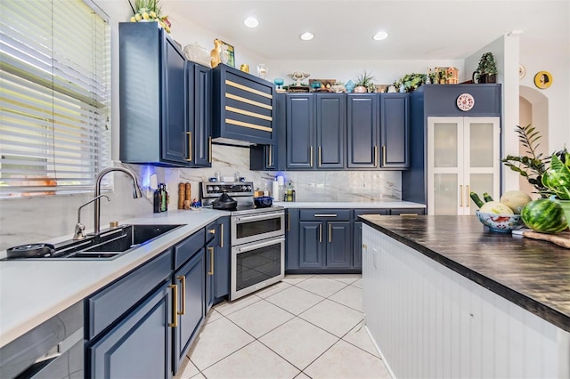 kitchen featuring range with two ovens, light tile patterned flooring, sink, and blue cabinets