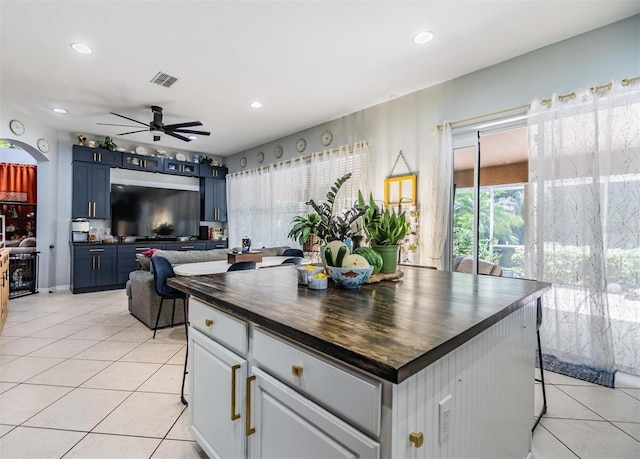 kitchen with butcher block countertops, light tile patterned floors, blue cabinetry, and ceiling fan