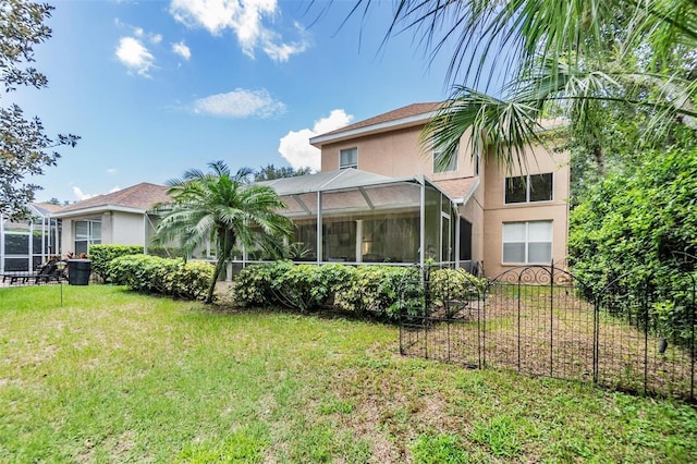 rear view of property with a yard and glass enclosure