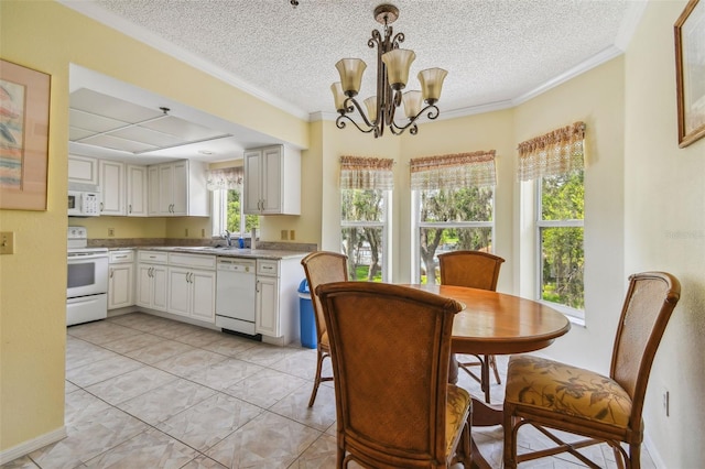 tiled dining space with sink, a textured ceiling, ornamental molding, and a chandelier