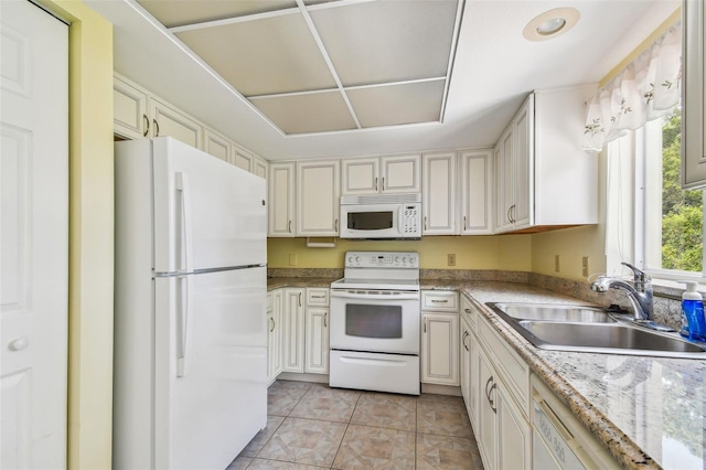 kitchen with light stone countertops, sink, light tile patterned floors, and white appliances