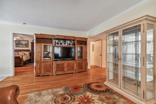 living room with ceiling fan, ornamental molding, light hardwood / wood-style floors, and a textured ceiling