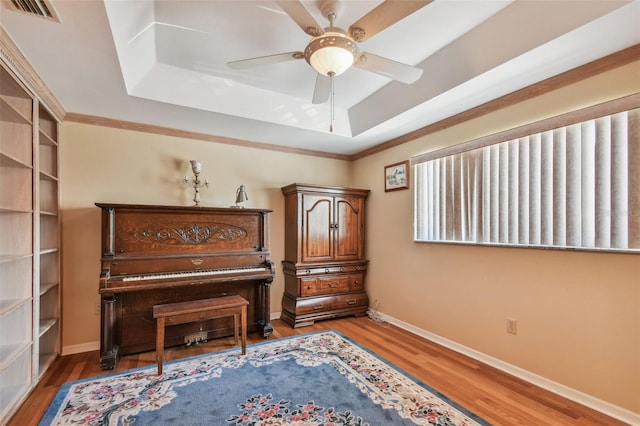 miscellaneous room featuring a raised ceiling, crown molding, hardwood / wood-style flooring, and ceiling fan