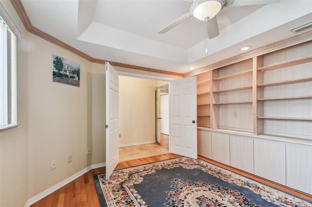 bedroom featuring a raised ceiling, ceiling fan, and light hardwood / wood-style flooring