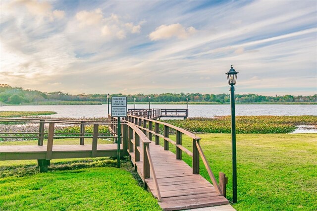 dock area with a water view and a yard