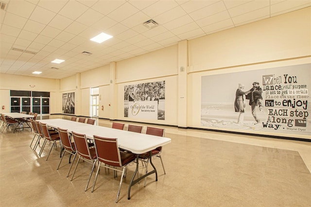 dining area featuring a towering ceiling and a paneled ceiling