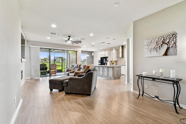 living room featuring a fireplace, light hardwood / wood-style flooring, and ceiling fan