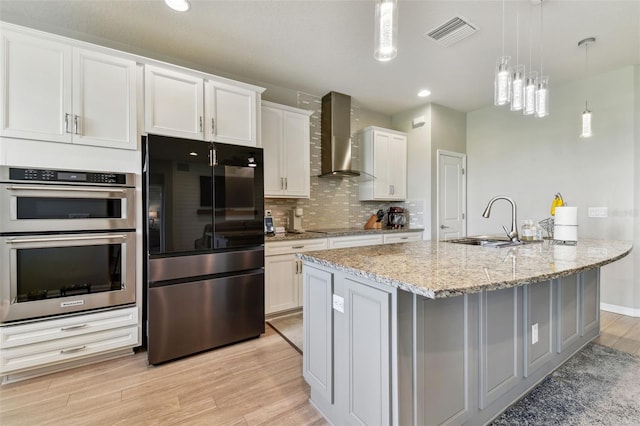 kitchen featuring white cabinetry, black appliances, wall chimney exhaust hood, and sink