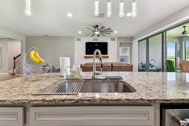 kitchen featuring hardwood / wood-style flooring, dishwasher, light stone countertops, brick wall, and ceiling fan