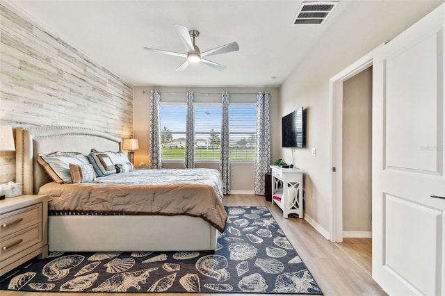 bedroom with wood walls, light hardwood / wood-style flooring, and ceiling fan