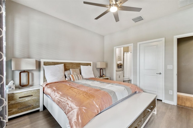 bedroom with ensuite bath, ceiling fan, and dark hardwood / wood-style flooring