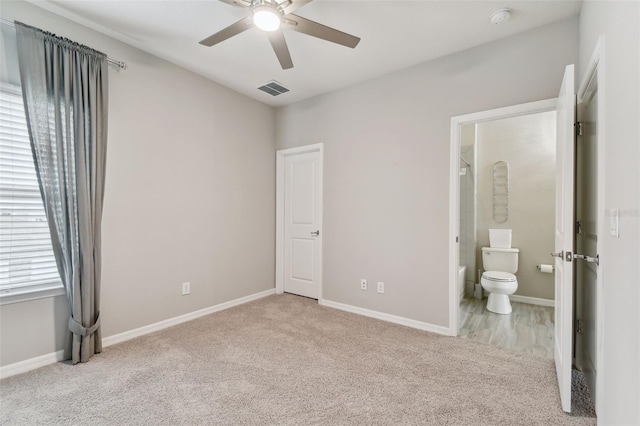 unfurnished bedroom featuring ensuite bath, light carpet, and ceiling fan