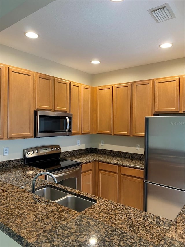 kitchen featuring recessed lighting, visible vents, appliances with stainless steel finishes, a sink, and dark stone counters