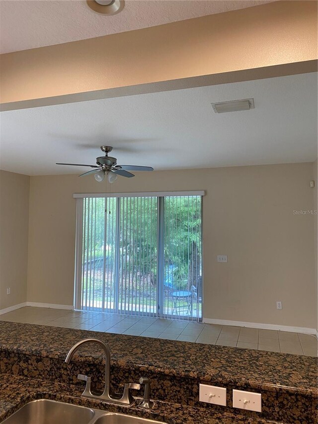 unfurnished room featuring ceiling fan, a sink, visible vents, baseboards, and tile patterned floors