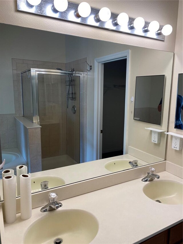 bathroom with a sink, a shower stall, and double vanity