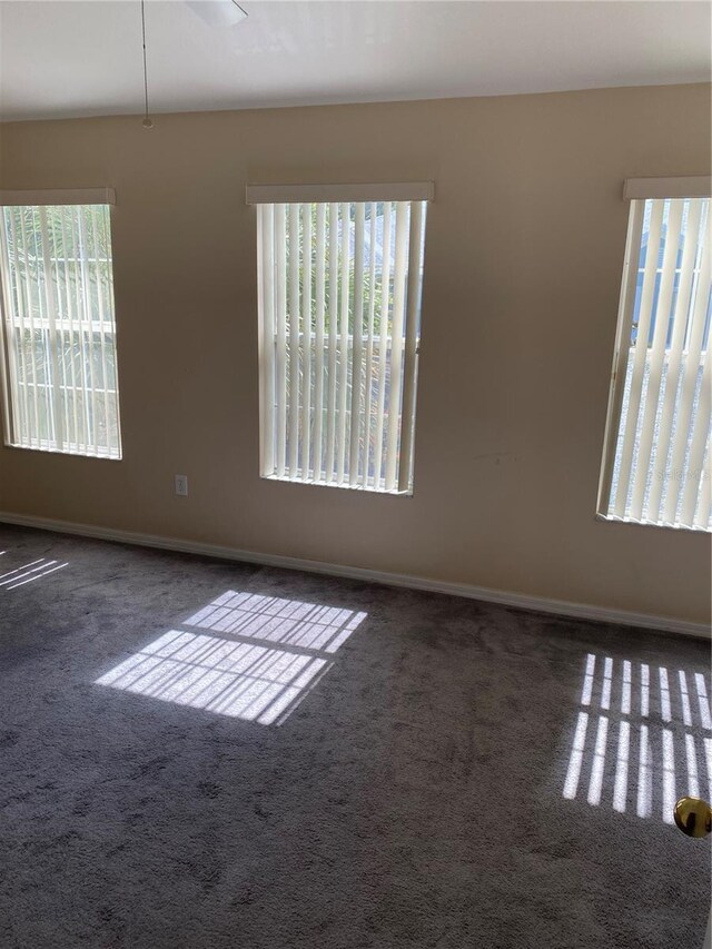 spare room with dark carpet and baseboards