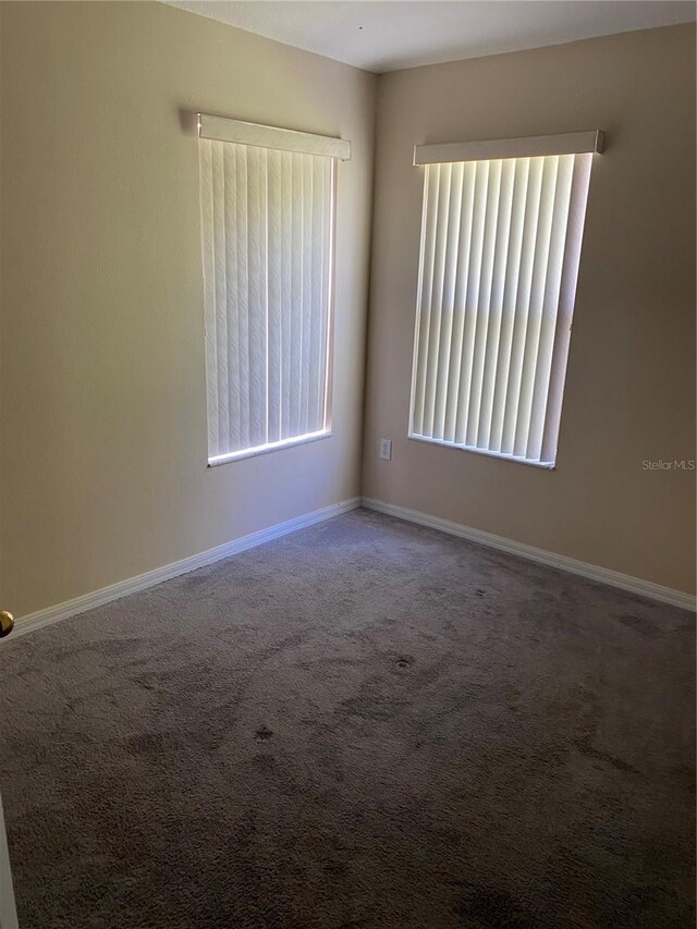 carpeted spare room featuring baseboards