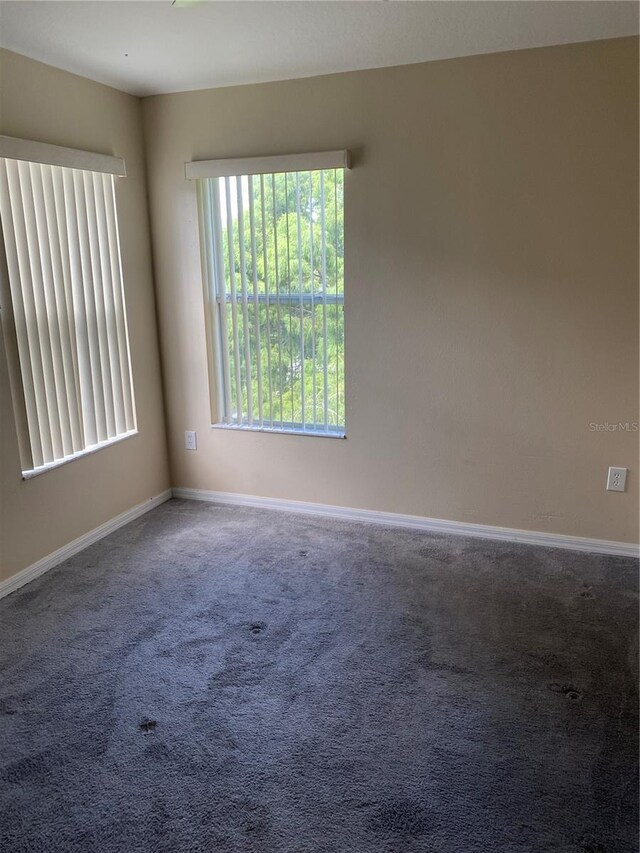 empty room featuring carpet and baseboards