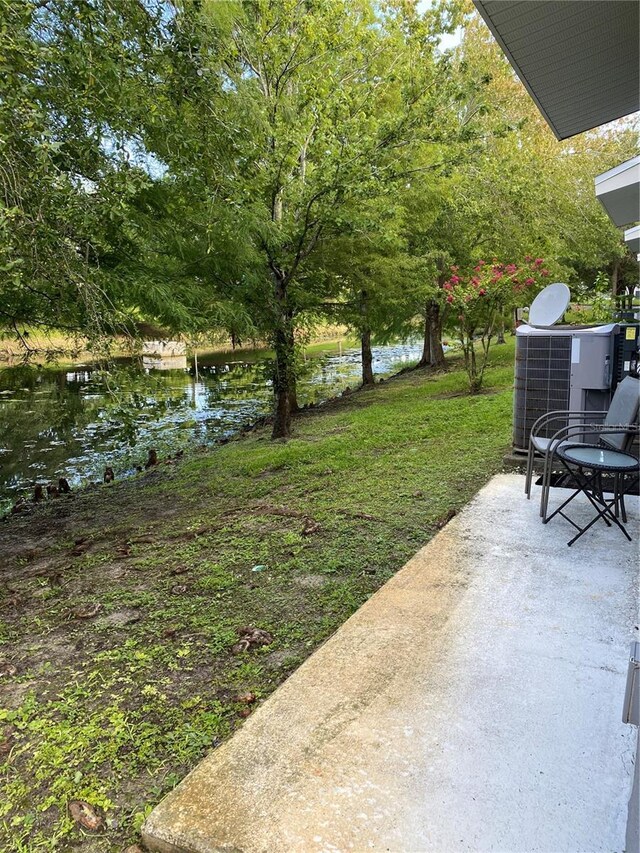 view of yard with a patio area, a water view, and central air condition unit