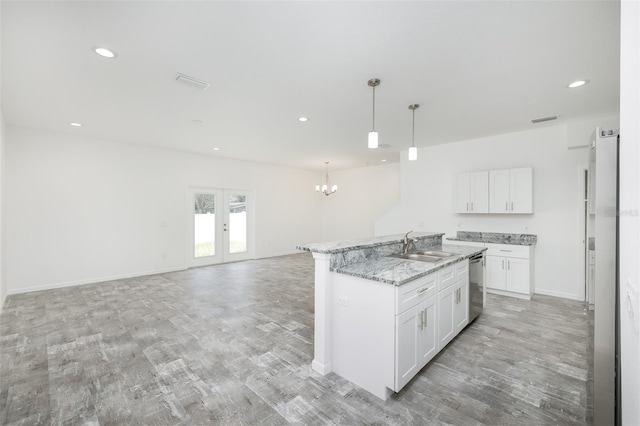 kitchen featuring pendant lighting, a kitchen island with sink, dishwasher, and white cabinets