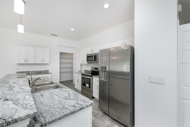 kitchen with sink, appliances with stainless steel finishes, white cabinetry, hanging light fixtures, and kitchen peninsula