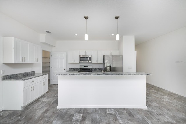 kitchen featuring stainless steel appliances, white cabinetry, hanging light fixtures, and a kitchen island with sink