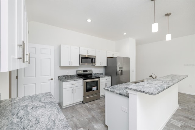 kitchen with pendant lighting, light stone countertops, stainless steel appliances, and white cabinets