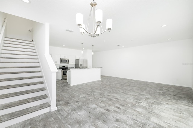 unfurnished living room featuring an inviting chandelier and light hardwood / wood-style flooring