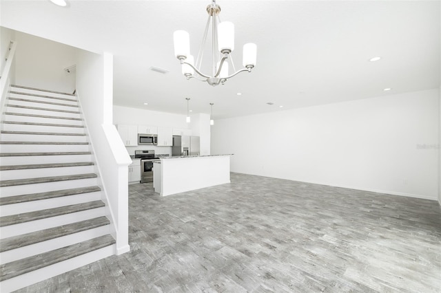 unfurnished living room with a chandelier and light wood-type flooring