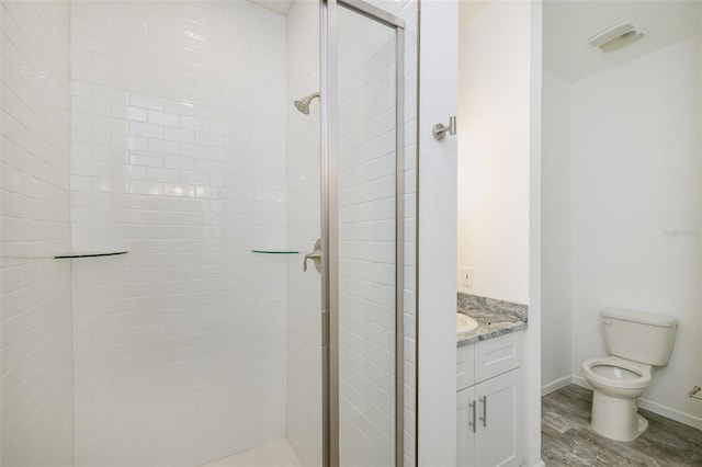 bathroom featuring tiled shower, wood-type flooring, toilet, and vanity