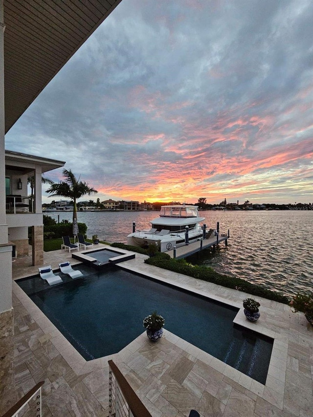 pool at dusk with a water view, a dock, and a patio