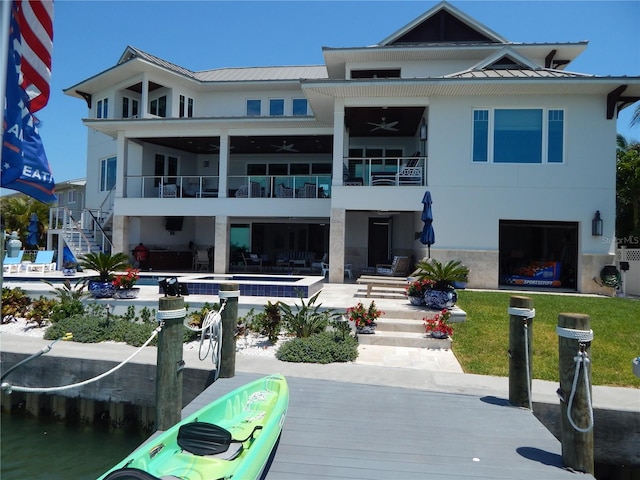 back of property with ceiling fan and a water view