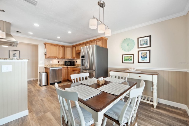 dining space with crown molding and light hardwood / wood-style floors