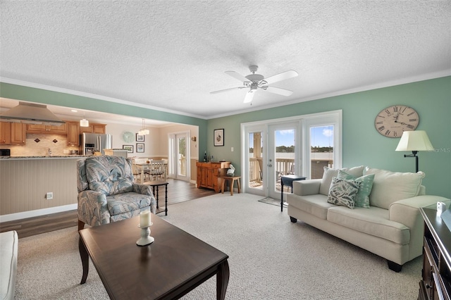 living room with a textured ceiling, ceiling fan, ornamental molding, and french doors