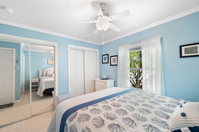 bedroom featuring a textured ceiling, ceiling fan, ornamental molding, and two closets