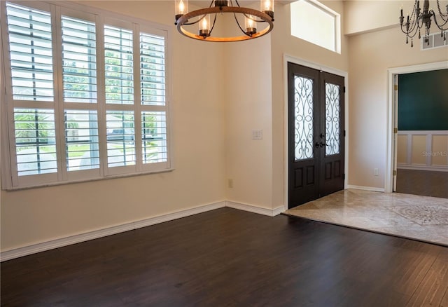 entrance foyer with french doors, a chandelier, and dark wood-type flooring