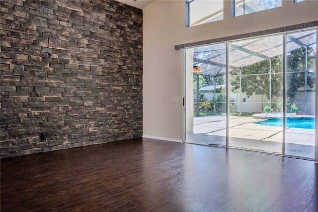 doorway with dark wood-type flooring, plenty of natural light, and a towering ceiling