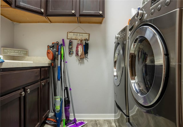 laundry room with cabinets, washing machine and dryer, and hardwood / wood-style floors