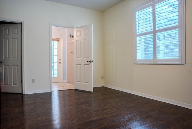 unfurnished bedroom with multiple windows and dark wood-type flooring