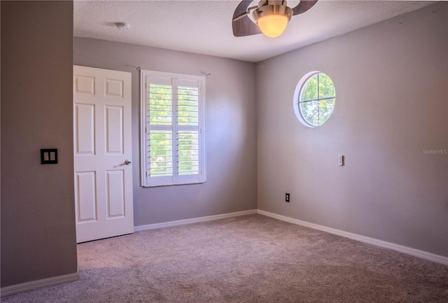 spare room featuring ceiling fan, light colored carpet, and a textured ceiling