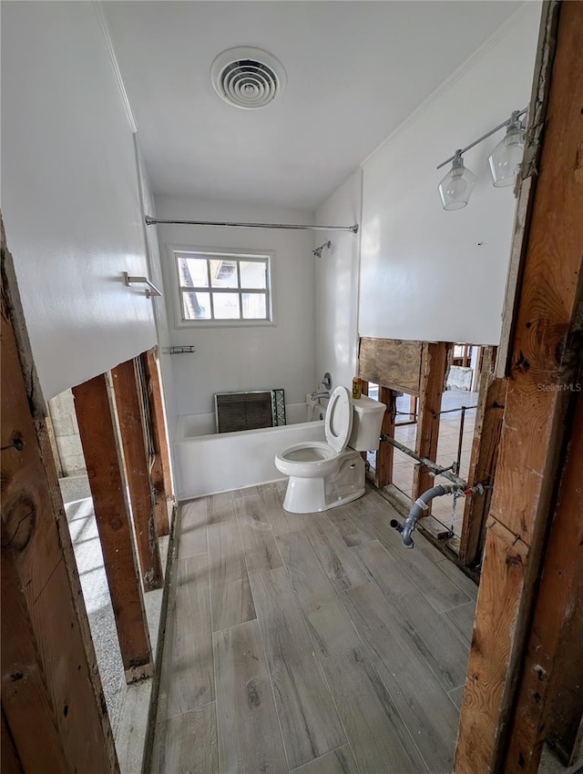 bathroom with hardwood / wood-style flooring, toilet, and crown molding