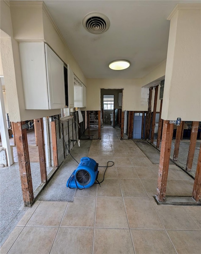 hallway featuring light tile patterned floors and ornamental molding