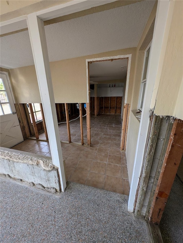 hallway featuring tile patterned floors and a textured ceiling