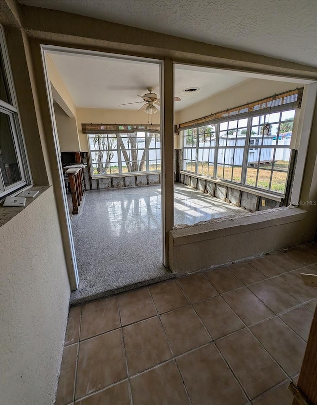 entryway featuring a textured ceiling, dark carpet, plenty of natural light, and ceiling fan