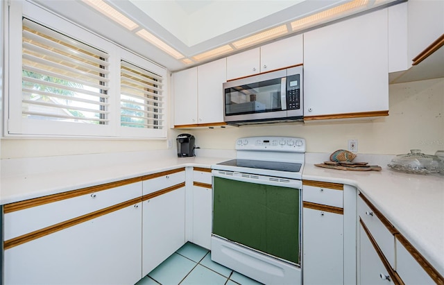 kitchen featuring electric range, white cabinets, and light tile patterned flooring