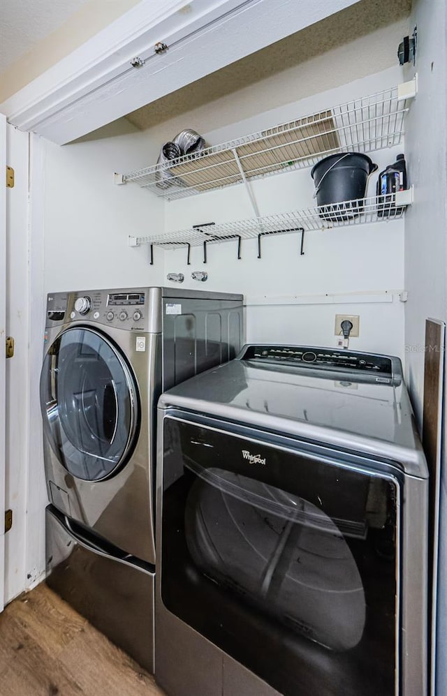 laundry area with washing machine and clothes dryer and wood-type flooring