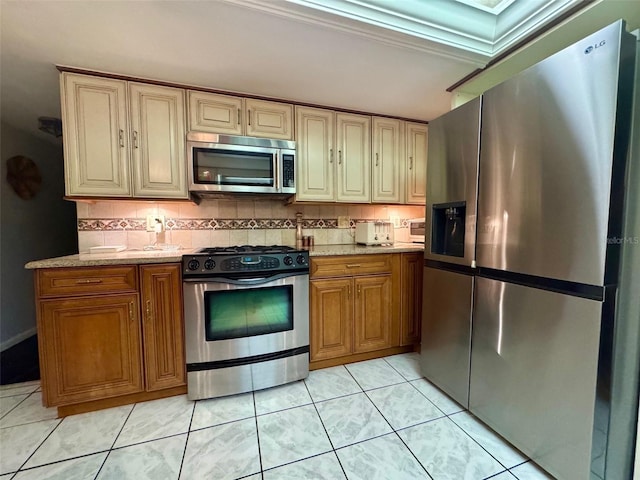 kitchen with light tile patterned flooring, appliances with stainless steel finishes, light stone counters, and tasteful backsplash