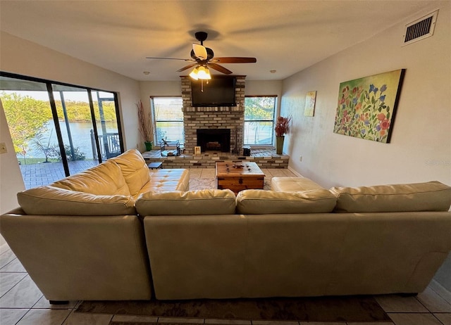 living room featuring a brick fireplace, light tile patterned floors, and ceiling fan