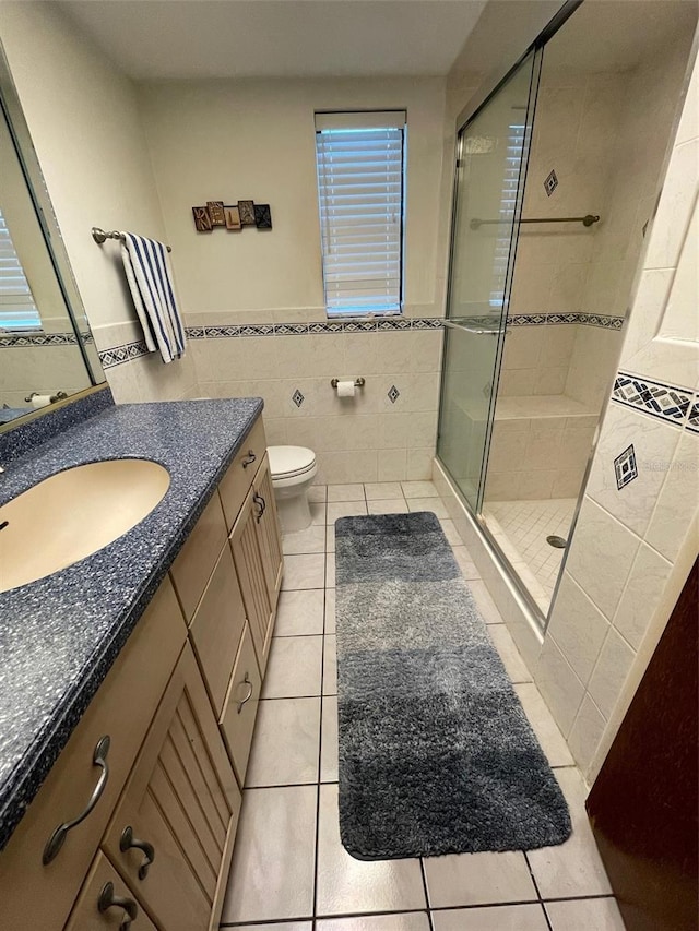 bathroom featuring tile walls, walk in shower, vanity, and tile patterned flooring