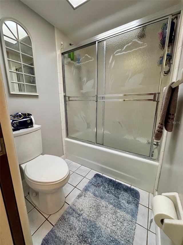 bathroom with toilet, tile patterned flooring, and shower / bath combination with glass door